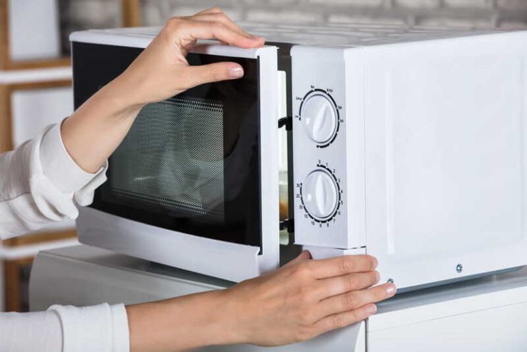 Une femme qui réchauffe son plat surgelé industriel au micro-ondes.