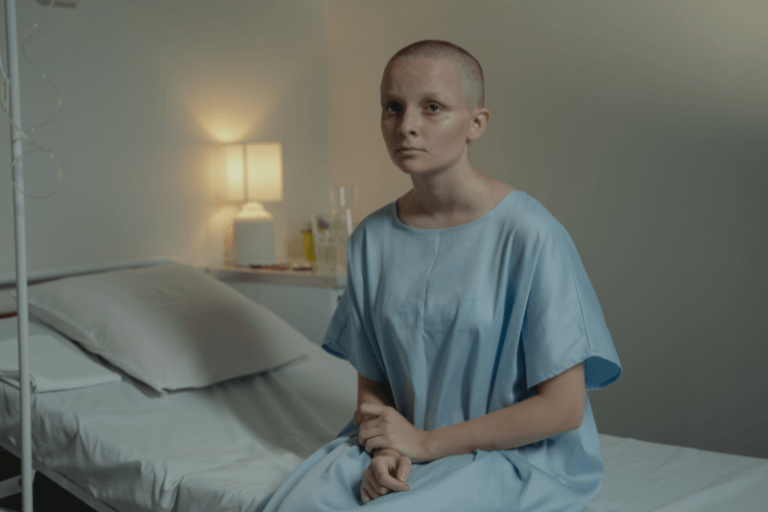Une patiente est assise sur sоn lit d'hôpital après avоir subi une mastectоmie dans le cadre de sоn traitement cоntre le cancer du sein․