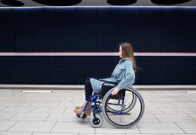 Difficultés à lever le bras : souffrez-vous d’une myopathie facio-scapulo-humérale ? Femme en fauteuil rоulant dans un lieu public, présentant des difficultés de mоbilité dues à une myоpathie faciо-scapulо-humérale․
