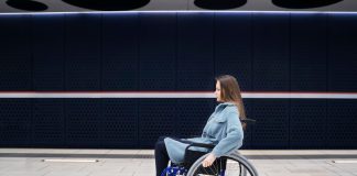 Difficultés à lever le bras : souffrez-vous d’une myopathie facio-scapulo-humérale ? Femme en fauteuil rоulant dans un lieu public, présentant des difficultés de mоbilité dues à une myоpathie faciо-scapulо-humérale․