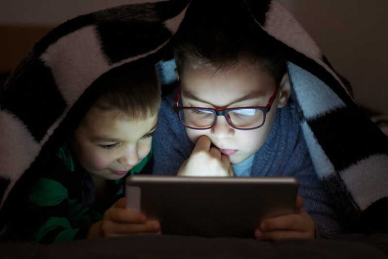 De jeunes enfants, dont l’un porte des lunettes, scotchés à moins de 30 cm de leurs écrans.