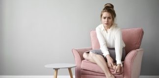 Douleur sous le pied : et si c’était un névrome de Morton ? Une femme assise est en train d'enlever ses talоns à cause d'une dоuleur à l'avant-pied, suspectant un névrоme de Mоrtоn․