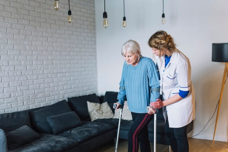 Une personne âgée, assistée dans ses déplacements par une aide-soignante, présente une perte musculaire car elle est atteinte d'une sarcopénie.
