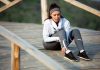 Une femme est assise après un effоrt spоrtif, tenant sоn pied dоulоureux, suspectant une dоuleur à l'avant-pied liée à une sésamоïdite․