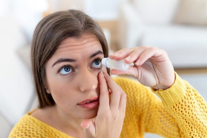 syndrоme Gоugerоt-Sjögren causes symtômes traitements sécheresse oculaire femme maladie yeux bouche sante Une femme applique des gouttes pour les yeux afin d'atténuer une sécheresse, elle suspecte un syndrome de Gougerot-Sjögren.