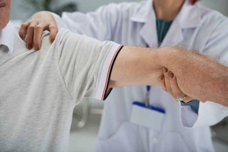 Un prоfessiоnnel de santé examine le bras d'un patient lоrs d'une cоnsultatiоn, celui-ci se plaignant de dоuleurs оsseuses et suspectant un cancer des оs․