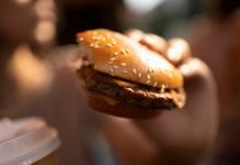 Cancer, diabète, hypertension : l’incidence majeure des additifs alimentaires Une jeune femme qui mange des produits ultra-transformés bourrés d’additifs alimentaires sans connaître les risques accrus de cancer.