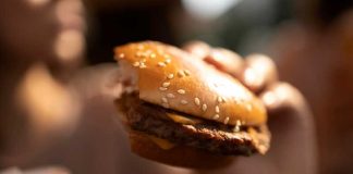Une jeune femme qui mange des produits ultra-transformés bourrés d’additifs alimentaires sans connaître les risques accrus de cancer.