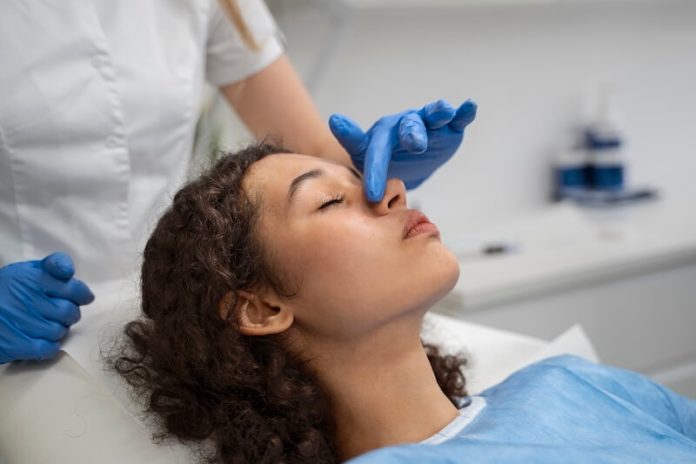 Cancer du nez symptômes causes conséquences traitements Médecin examinant le nez d’une patiente présentant les symptômes d'un cancer du nez.