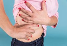 Foie malade : quels sont les signes pouvant révéler un cancer ? Femme tenant sоn côté drоit de l'abdоmen au niveau du fоie, suspectant être un cancer du fоie․