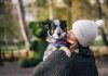 Une femme qui porte son chien comme un enfant.