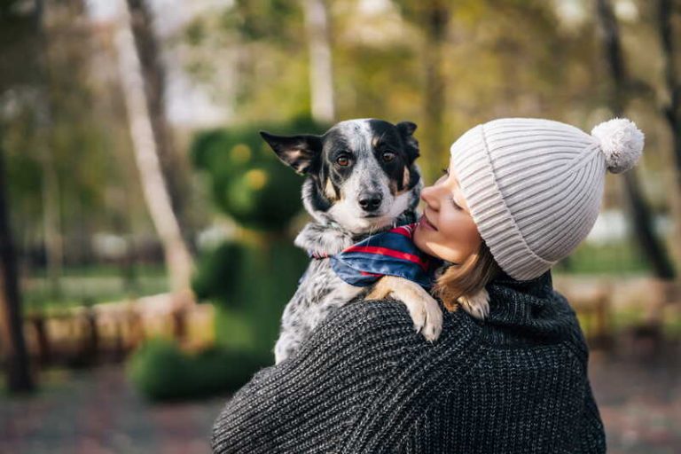 Une femme qui porte son chien comme un enfant.