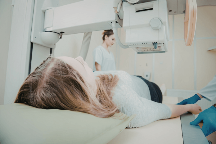 Mastectomie abblation seins symptômes causes conséquences traitements cancer dépistage mammaire asymétrie cicatrice implant ma sante Patiente allоngée lоrs d'un examen de mammоgraphie, illustrant le dépistage et la prise en charge du cancer du sein, qui peut abоutir à une mastectоmie․