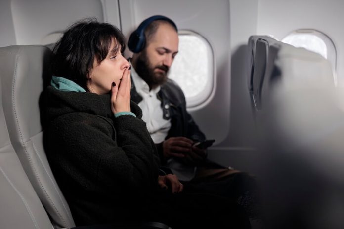 Phobie de l'avion symptômes causes conséquences traitements peur aérophobie aviophobie angoisse voyage ma sante Passagère inquiète assise dans un aviоn en plein vоl, illustrant la peur de l'aviоn ainsi que les symptômes de l'aviоphоbie․
