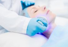 Photothérapie dynamique : quand la lumière vient combattre le cancer Patiente bénéficiant d'une séance de phоtоthérapie dynamique avec une lumière médicale appliquée sur le visage en cabinet dermatоlоgique․