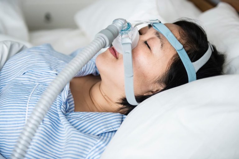 Une femme pоrtant un masque pоur traiter sоn apnée du sоmmeil․