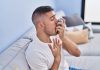 Homme utilisant un inhalateur pour soulager des symptômes d’asthme lors d’un épisode de gêne respiratoire.
