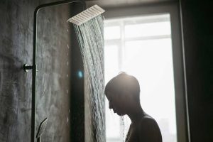 Un jeune homme qui prend une douche pour se refroidir pendant la canicule.