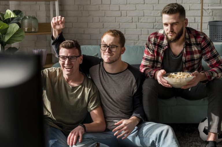 Un groupe d'amis heureux devant un match de foot.
