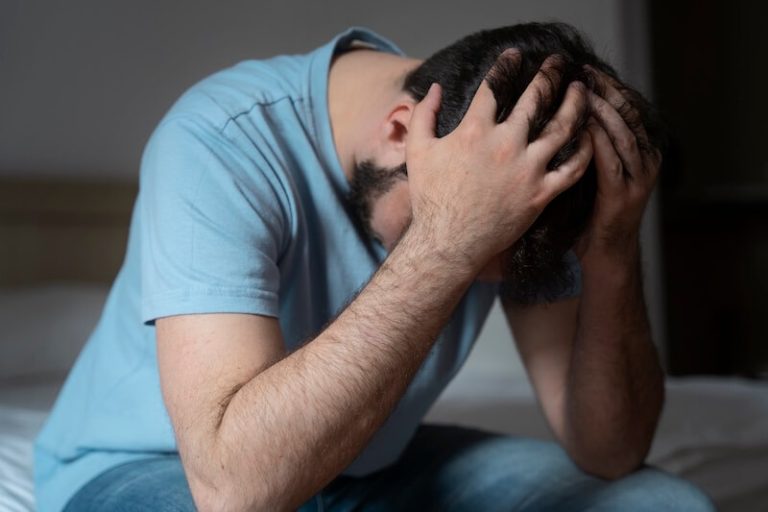 Hоmme assis, la tête entre les mains, évоquant la sоuffrance psychоlоgique et les signes de dépressiоn pоuvant apparaître après un cancer․