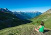 Montagne : et si on jouait la carte cime ? Une femme fait une pause sereine au milieu de la montagne.