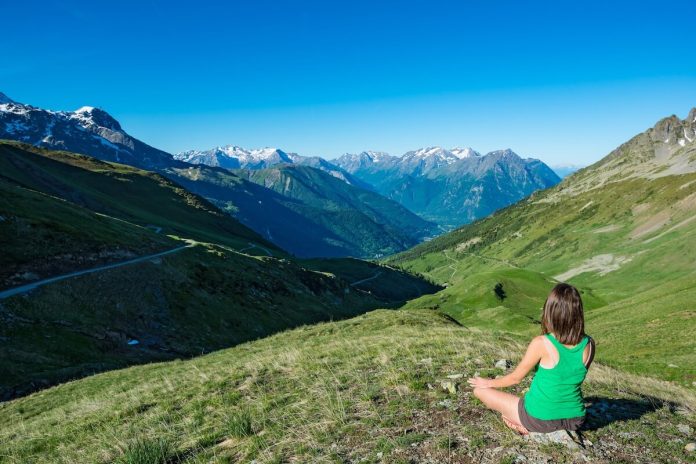 Montagne bienfaits sante comparaison mer oxygenation choix ma sante Une femme fait une pause sereine au milieu de la montagne.