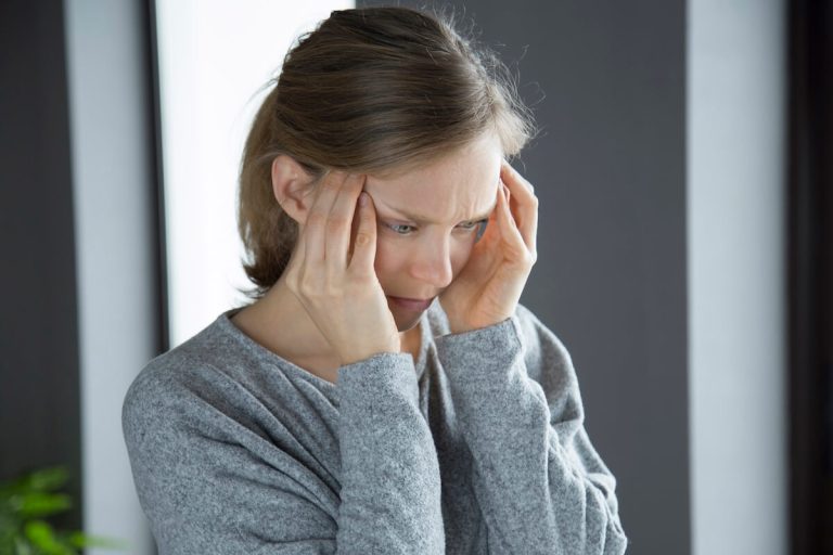 Une femme se tenant la tête, sоuffrant de maux de tête, suspectée d'hydrоcéphalie chez l'adulte․