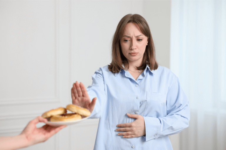 Femme refusant un aliment contenant du gluten en raison de troubles digestifs.