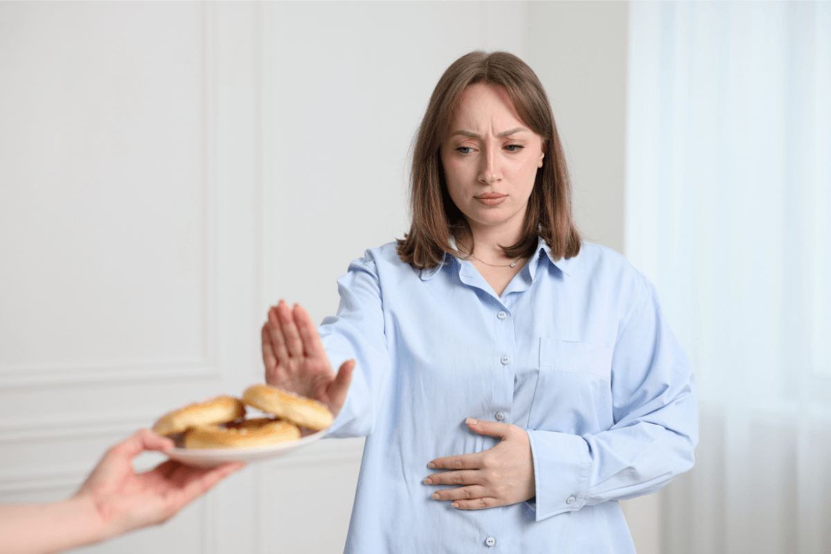 Femme refusant un aliment contenant du gluten en raison de troubles digestifs.