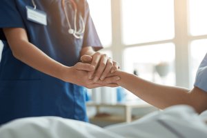 Professionnel de santé tenant la main d’un patient hospitalisé.