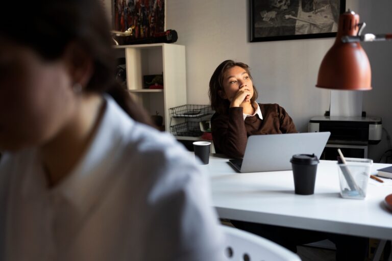 Une jeune salariée, assise à son bureau, le regard perdu dans le vide, montre les premiers signes d'un burn-out.