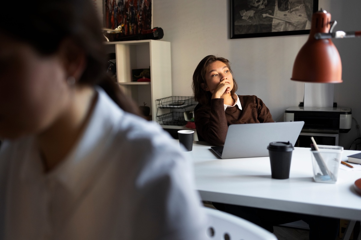 Une jeune salariée, assise à son bureau, le regard perdu dans le vide, montre les premiers signes d'un burn-out.