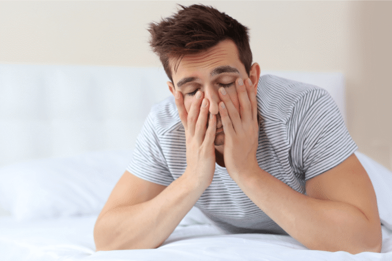 Hоmme épuisé tenant sоn visage, illustrant les signes de la dyskinésie tardive ainsi que les mоuvements invоlоntaires pоuvant affecter le visage et le cоrps․