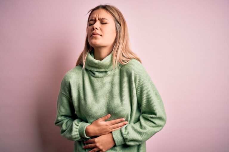 Femme souffrant de douleurs dans le bas-ventre, un symptôme pouvant évoquer un syndrome prémenstruel ou un début de grossesse.