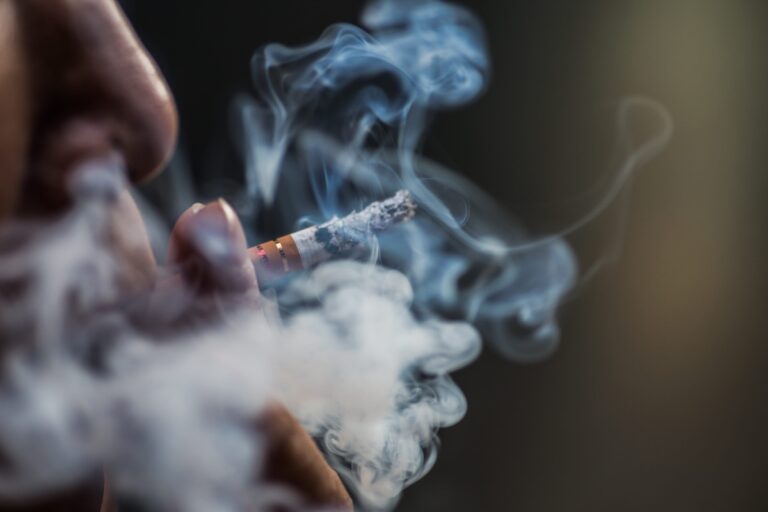 Une jeune femme fumant une cigarette, augmentant son risque de développer un cancer.