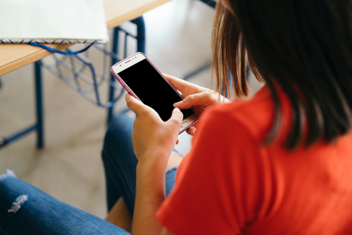 Une jeune lycéenne distraite par son téléphone pendant un cours.