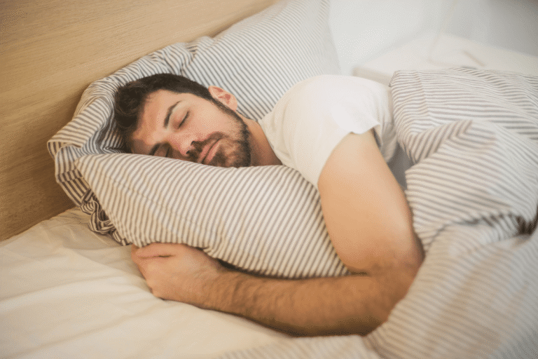 Homme endormi dans un lit, serrant un oreiller.