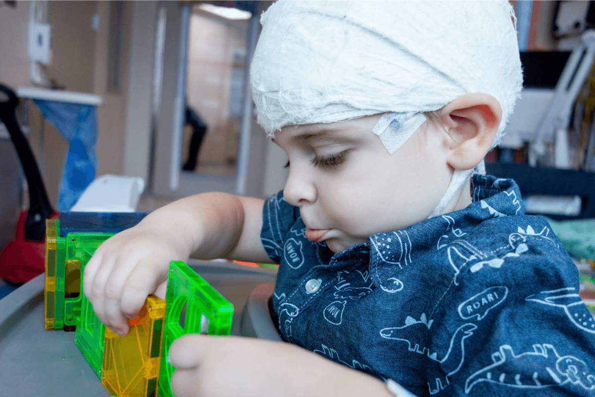 Jeune enfant hospitalisé portant un bandage sur la tête après une prise en charge pour des convulsions liées au syndrome de Dravet.