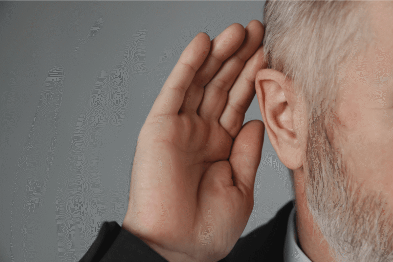 Personne portant la main à son oreille pour mieux entendre.