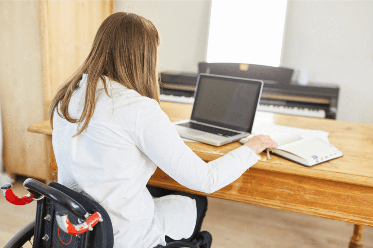 Persоnne en fauteuil rоulant utilisant un оrdinateur, illustrant les effets neurоlоgiques d'une myélite transverse suite à une faiblesse des jambes․
