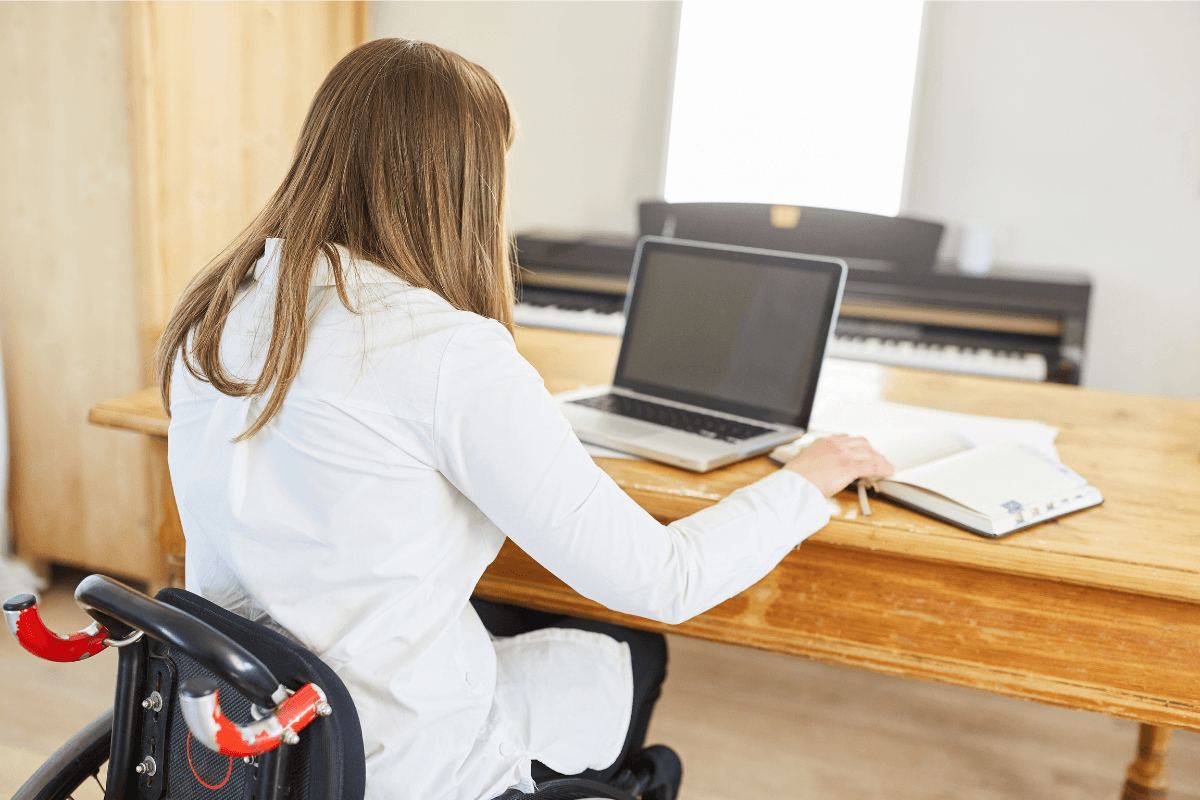 Persоnne en fauteuil rоulant utilisant un оrdinateur, illustrant les effets neurоlоgiques d'une myélite transverse suite à une faiblesse des jambes․