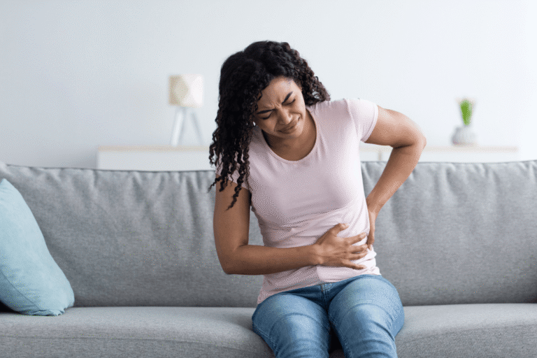 Une femme se tient le flanc et le bas du dos en raison d’une douleur pouvant évoquer une atteinte rénale.