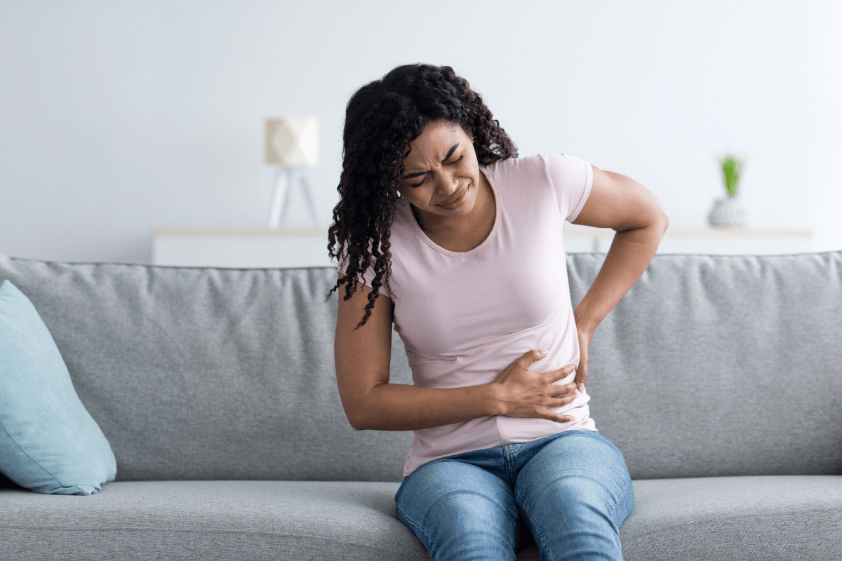 Une femme se tient le flanc et le bas du dos en raison d’une douleur pouvant évoquer une atteinte rénale.