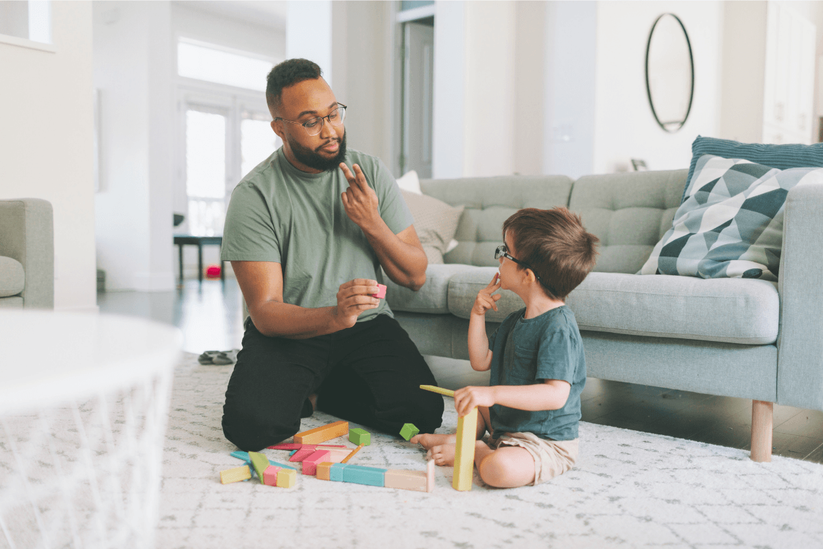 Parent communiquant par gestes avec un jeune enfant atteins du syndrome de Landau-kleffner lors d'un jeu.