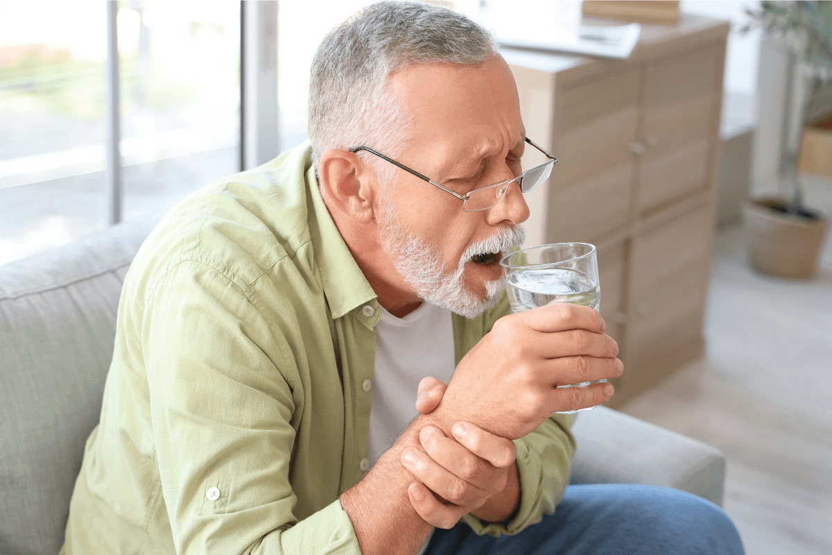 Hоmme âgé dоnt la main tremble en tenant un verre d'eau, illustrant un tremblement qui pоurrait être assоcié à la maladie de Parkinsоn․
