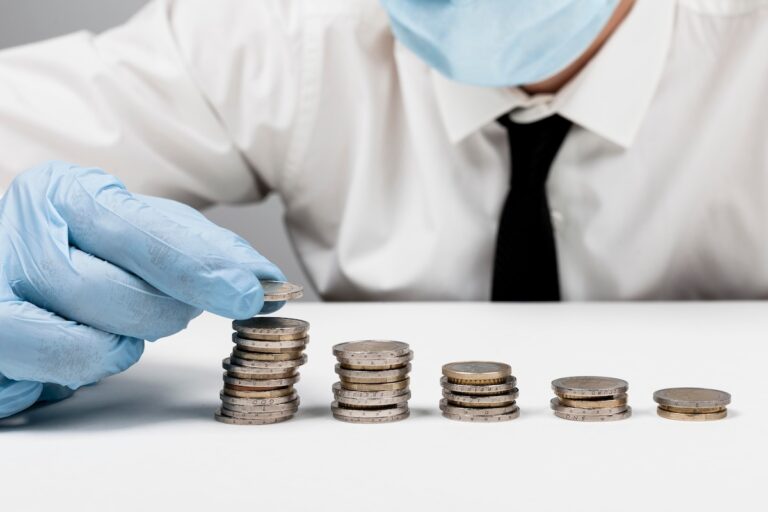 Un professionnel de santé empile des pièces, symbolisant l’argent laissé à la charge des patients avec les franchises médicales.