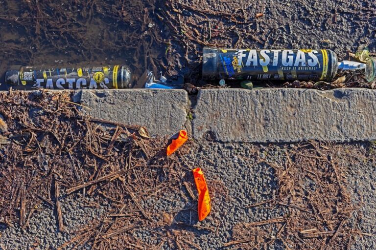 Deux bonbonnes de protoxyde d’azote grossièrement jetées sur le bord de la route.
