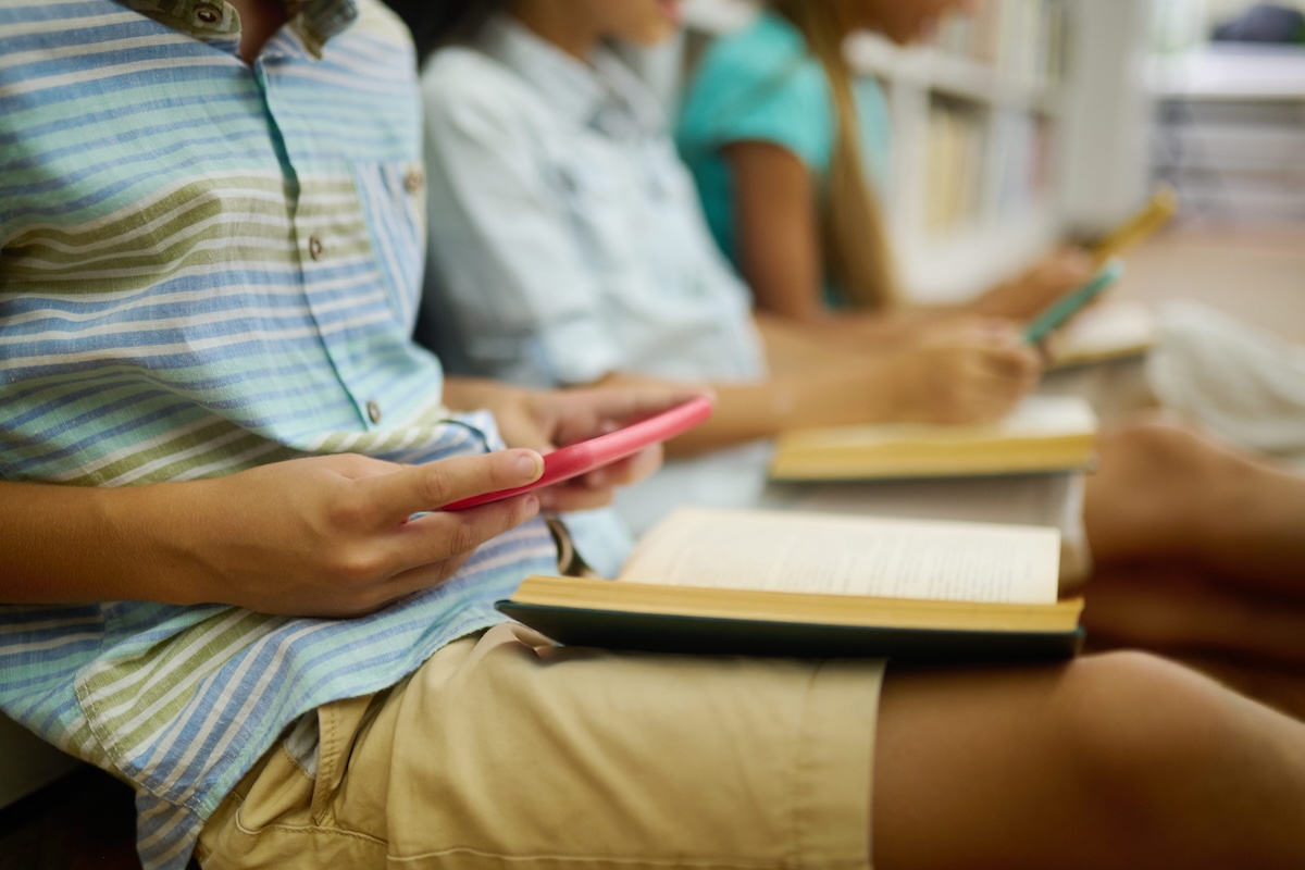 Des adolescents de moins de 15 ans sur leur téléphone, en train de consulter les réseaux sociaux.