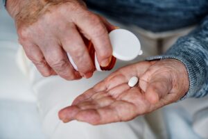 Une personne âgée prend un complément alimentaire à base de vitamine D pour ralentir son déclin cognitif lié à la maladie d’alzheimer.