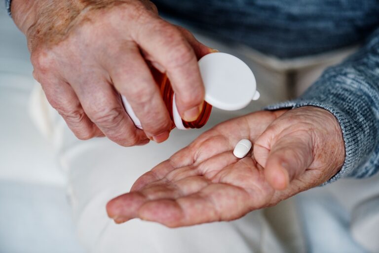 Une personne âgée prend un complément alimentaire à base de vitamine D pour ralentir son déclin cognitif lié à la maladie d’alzheimer.